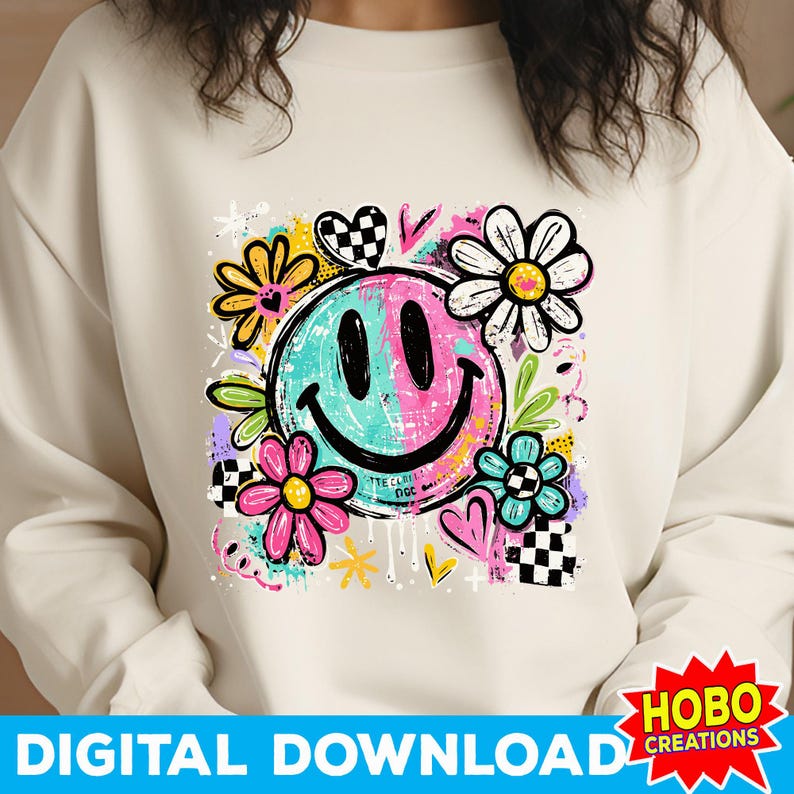 May include: Cream-colored sweatshirt featuring a colorful smiley face design. The graphic includes a split turquoise and pink smiley face, surrounded by flowers, hearts, and checkered patterns. Text at the bottom reads "DIGITAL DOWNLOAD".