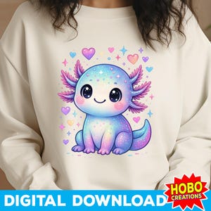 K&ouml;nnte beinhalten: Cremefarbenes Sweatshirt mit einem bunten Cartoon-Axolotl-Design. Der Axolotl ist blau, lila und rosa, mit gro&szlig;en schwarzen Augen und einem l&auml;chelnden Gesicht. Herzen und Sterne umgeben den Axolotl. Der Text "DIGITAL DOWNLOAD" ist unten aufgedruckt.