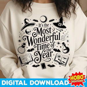 May include: A white sweatshirt with a black graphic design featuring a witch's hat, a skull, a potion bottle, a book, and the text "It's the Most Wonderful Time of the Year".