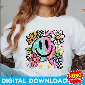 May include: White t-shirt featuring a colorful smiley face design. The graphic includes a split face in teal and pink, surrounded by flowers, hearts, and checkerboard patterns. The words "DIGITAL DOWNLOAD" are at the bottom.