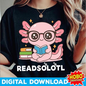 May include: Black t-shirt featuring a cartoon axolotl wearing glasses and reading a book. The axolotl is pink with a stack of books next to it. The text "READSÖLÖTL" is below the axolotl.