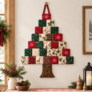 May include: A wall-hanging fabric Christmas tree composed of quilted square patches in red, green, and cream. The patches feature patterns of snowflakes, poinsettias, holly, and deer. A brown fabric trunk is attached at the base of the tree.