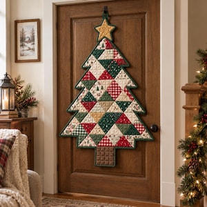 Pode incluir: Um enfeite de parede de árvore de Natal acolchoado com um design de patchwork de triângulos de tecido vermelho, verde, creme e xadrez. A árvore é rematada com uma estrela dourada, tem um tronco quadrado castanho e um rebordo verde escuro.