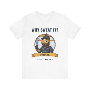 May include: A white short-sleeve t-shirt featuring a graphic of a cartoon character wearing a black cap and a blue plaid shirt. The character holds a small spray bottle. Text reads WHY SWEAT IT? PRESS IT. and HONEST BOB CO. at the bottom.