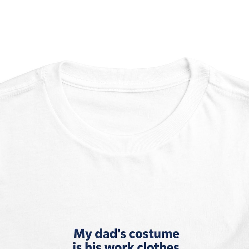 May include: A white crew neck t-shirt featuring dark blue text printed on the front. The text reads, My dad's costume is his work clothes. The garment has a standard ribbed collar and short sleeves, showcasing a clean and simple design.