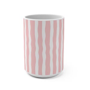 May include: A cylindrical ceramic mug featuring a repeating pattern of vertical, wavy stripes in soft pastel pink and white. The mug has a smooth, matte-finish exterior and a clean, white interior rim, showcasing a simple, modern, and minimalist design.