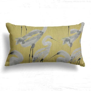 May include: Rectangular decorative pillow with a yellow background and a watercolor pattern of white and gray herons. The pillow has a soft, textured appearance, perfect for adding a touch of nature-inspired decor to any room.