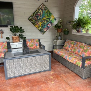 May include: A patio furniture set featuring a rectangular coffee table with a gray woven base and a dark top, two armchairs, and a three-seat sofa. All seating pieces have dark frames and cushions with a vibrant, multi-colored tropical leaf pattern.
