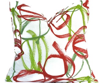 May include: A white throw pillow with a red and green abstract design. The design features brushstrokes and swirls.