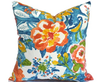 May include: A white pillow with a colorful floral pattern. The flowers are in shades of orange, yellow, blue, and green. The pillow is perfect for adding a touch of color and style to any room.