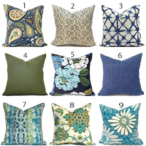 May include: Nine decorative throw pillows with various patterns and colors. Pillows include paisley, geometric, floral, and solid designs. Colors include blue, green, beige, and white. The pillows are square-shaped and appear to be made of fabric.
