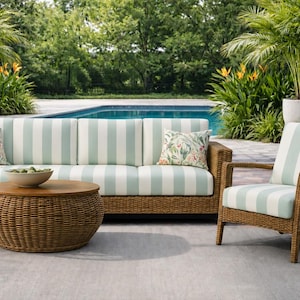 May include: An outdoor furniture set consisting of a three-cushion sofa and a matching armchair with woven brown frames and light blue and white striped cushions. A round, woven brown coffee table sits in front of the sofa.