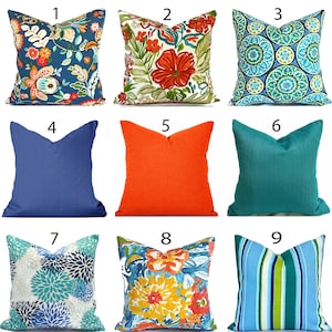 May include: Nine decorative throw pillows in various designs. Pillows include floral patterns in blue, orange, and yellow, solid colors in blue, orange, and teal, and a striped pattern in blue and green. The pillows are square and appear to be made of fabric.