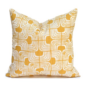 May include: A yellow throw pillow with a white geometric pattern. The pattern is made up of repeating arches and squares.