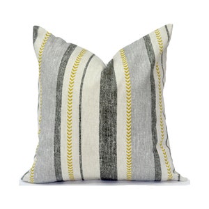 May include: A gray and white striped throw pillow with yellow chevron accents. The pillow is made of a soft, textured fabric.