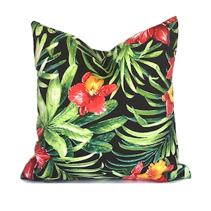 May include: A black pillow with a tropical print featuring red and yellow flowers and green leaves.