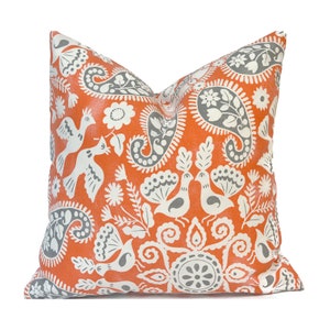 May include: Orange and gray throw pillow with a paisley and bird pattern.