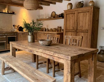 May include: A rustic dining set featuring a long, rectangular wooden table with a matching bench and two chairs. The furniture is crafted from light brown, weathered wood with visible grain. A metal pitcher with greenery sits on the table.