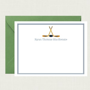 May include: A white card with a blue border and a hockey stick graphic. The text "Ryan Thomas Mackenzie" is printed below the graphic.