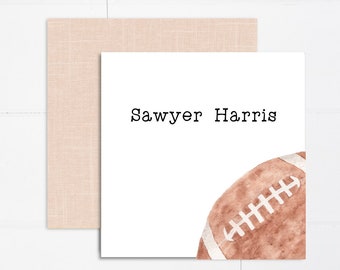 May include: A white card with the name "Sawyer Harris" printed in black text. A brown and white football graphic is in the bottom right corner of the card.
