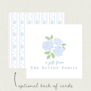 May include: White card with a blue hydrangea illustration and the text "a gift from THE SUTTON FAMILY." The card is paired with a patterned card featuring blue stripes and floral accents. The text "optional back of cards" is also present.