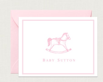 May include: Pink baby shower stationery with a pink rocking horse illustration and the text "BABY SUTTON".