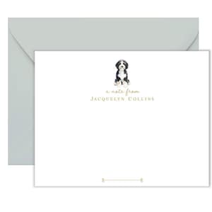 May include: White stationery set with a light grey envelope. The stationery features a watercolour illustration of a black and white dog above the text "a note from JACQUELYN COLLINS". A gold line with decorative ends is at the bottom.