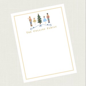 May include: White stationery with a gold border. The top of the page features a blue and gold illustration of a Christmas tree and five nutcracker figures. The text "THE COLLINS FAMILY" is written in gold below the illustration.