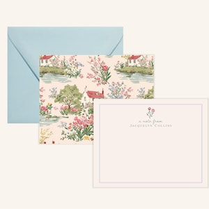 May include: Stationery set featuring a light blue envelope, a patterned card with a landscape design, and a blank card with a floral accent. The patterned card showcases a scenic view with houses, trees, and flowers. The blank card has the text "a note from Jacquelyn Collins."