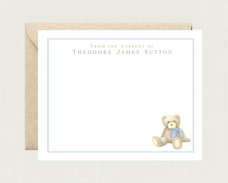 May include: A white card with a blue border and the text "From the Nursery of Theodore James Sutton". A brown teddy bear with a blue ribbon is sitting in the bottom right corner of the card.