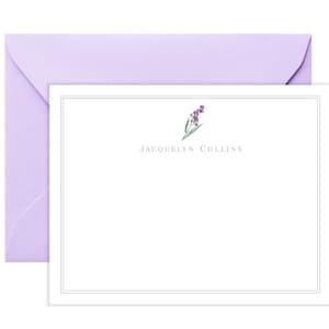 May include: A white stationery card with a thin black border. The card features a small purple flower illustration and the text "JACQUELYN COLLINS" in a gray font.