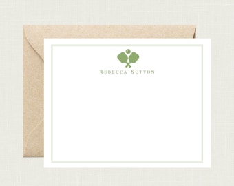 May include: A white card with a green border and a green illustration of two paddleball paddles and a ball. The text "Rebecca Sutton" is printed in green below the illustration.