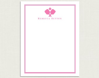 Peut inclure: Une carte de papeterie blanche avec une bordure rose et un graphique rose de raquette de paddle-tennis et de balle. Le texte "Rebecca Sutton" est imprimé en noir en haut de la carte.