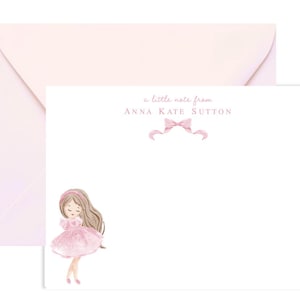 May include: A white card with pink text that reads "a little note from ANNA KATE SUTTON" with a pink bow above the text. A pink-dressed girl with brown hair is illustrated at the bottom of the card.