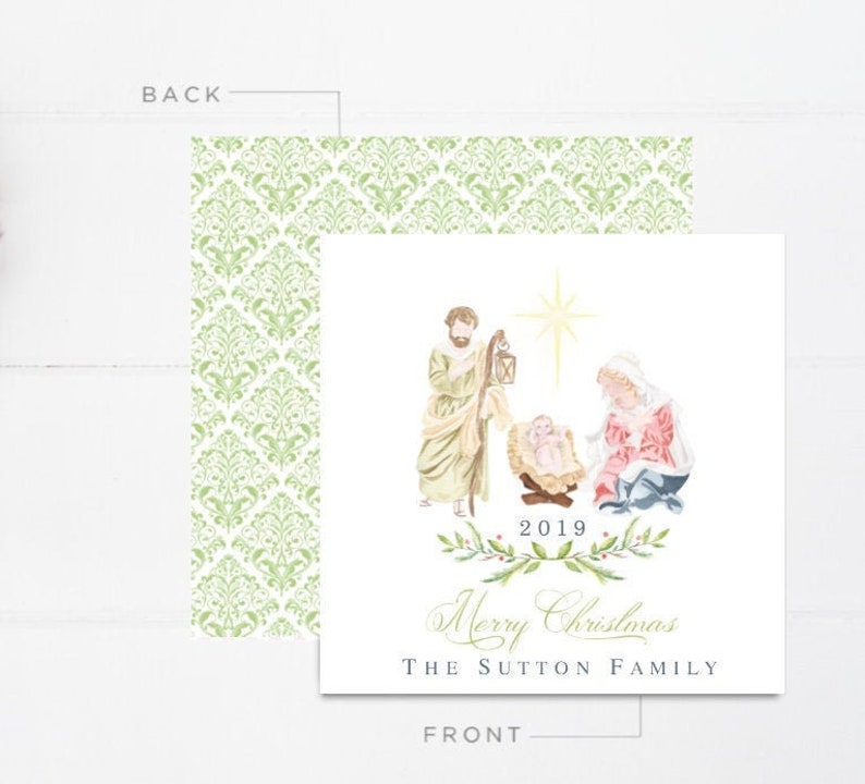 May include: A Christmas card featuring a watercolour illustration of the nativity scene. The card is white with green and gold accents. The text on the card reads "2019 Merry Christmas The Sutton Family".