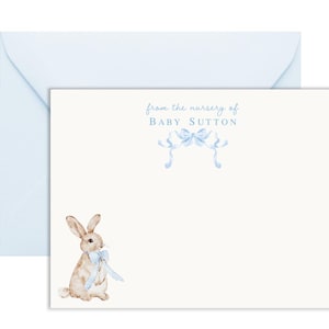 Puede incluir: Una tarjeta blanca con lazos de cinta azul y el texto "from the nursery of Baby Sutton". Un conejito marr&oacute;n con un lazo azul est&aacute; en la esquina inferior izquierda.