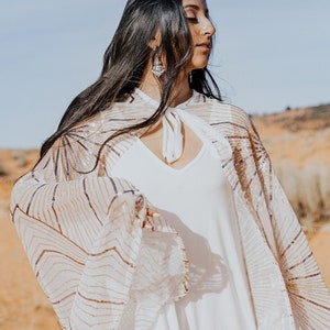 a woman in a white dress standing in the desert