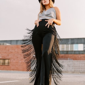 a woman wearing a hat and black fringe pants