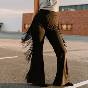 a woman in a wide legged pants and a hat