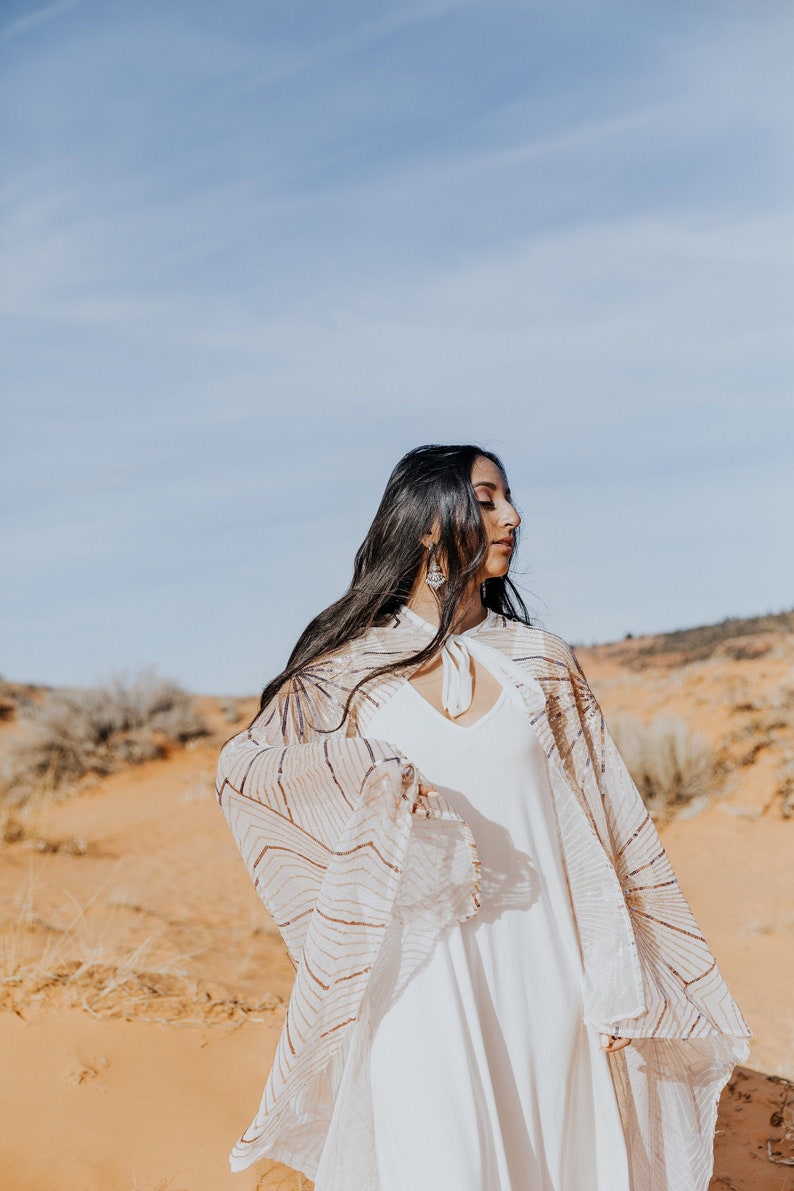 a woman in a white dress standing in the desert