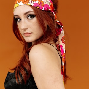 a woman with red hair wearing a bandana