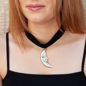 a woman wearing a necklace with a crescent moon on it