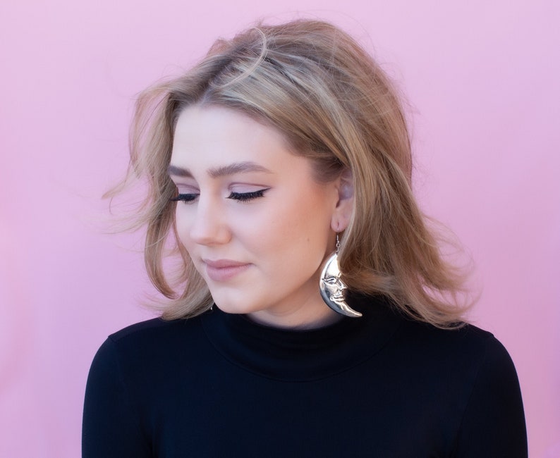 a woman wearing a black shirt and a pair of earrings