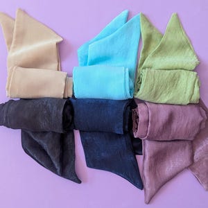 May include: Six satin fabric hair ties in different colors: beige, light blue, green, black, navy blue, and mauve.