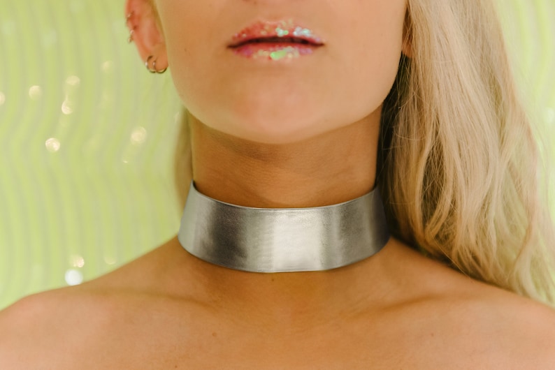a woman wearing a silver choker and a green background