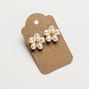 a pair of white flower shaped earrings on a card