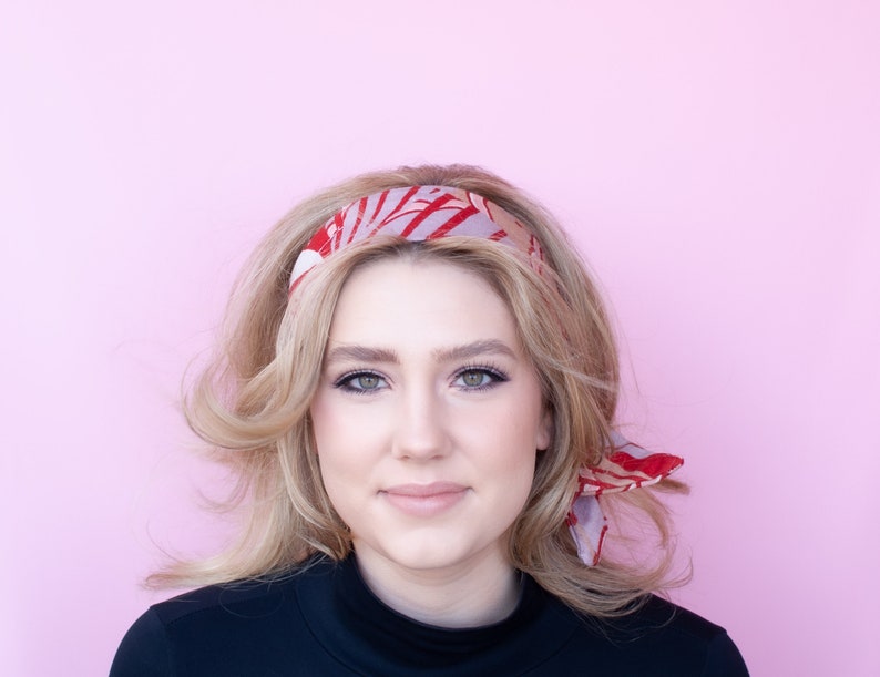 a woman with blonde hair wearing a red and pink head scarf