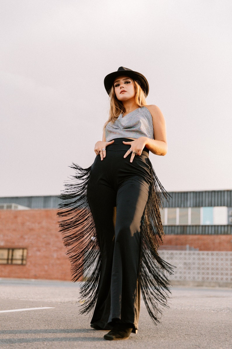 a woman wearing a hat and black fringe pants