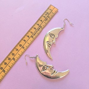 moon shaped earrings next to measuring tape