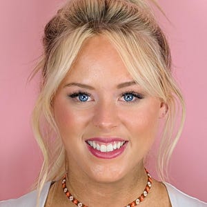 A close-up portrait of the woman showing her face and the floral choker necklace in detail.